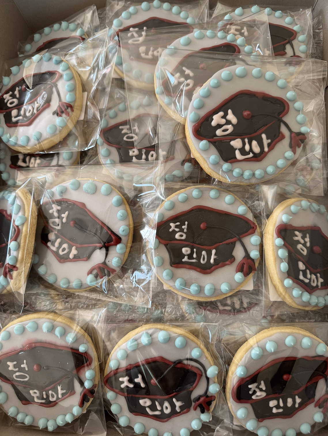 Graduation cap cookies with hand-piped names and pale blue pearl borders